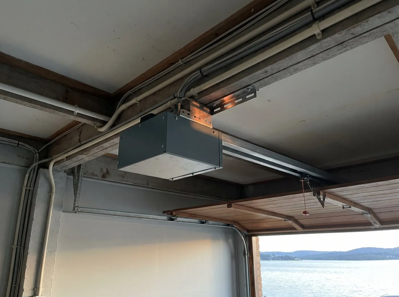 A garage door opener motor unit mounted on its rail under a garage ceiling